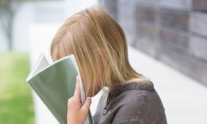 Girl holding a book in front of her face