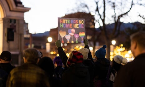 Person holding a sign with "Hate has no home here" at a vigil at dusk in Colorado Springs