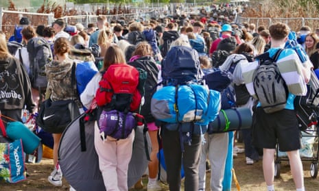 Crowds of young people loaded up with camping gear queue to enter the Reading festival site