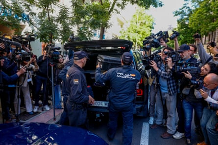 Police officers load boxes into the back of a vehicle