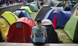 An Extinction Rebellion activist sits in front of tents at Marble Arch in London
