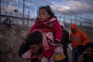 Texas, US. Briana, a one-year-old girl from Peru, is carried by her father as they search for an entry point into the US past a razor wire fence along the banks of the Rio Grande in El Paso