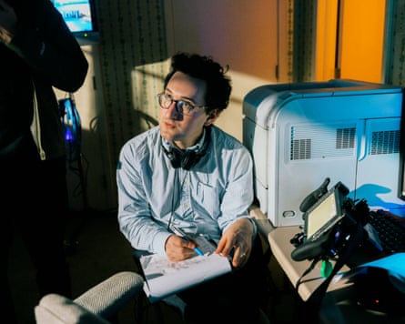 A man with glasses and headphones around his neck makes notes on a pad of paper.