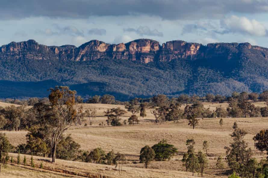 Capertee Valley, NSW, AustraliePlaines herbeuses adossées à une brousse naturelle et à des crêtes de grès accidentées dans la vallée de Capertee, NSW, Australie