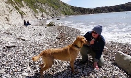 Allie on a pebble beach with a dog and an ice-cream.