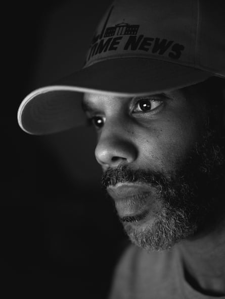 A bearded man in a baseball cap looks intently at, presumably, a computer screen.