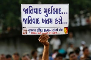 A man holds a placard that reads ‘Down with racism, finish racism’, during a rally protesting about atrocities against Dalits, in Ahmadabad, India