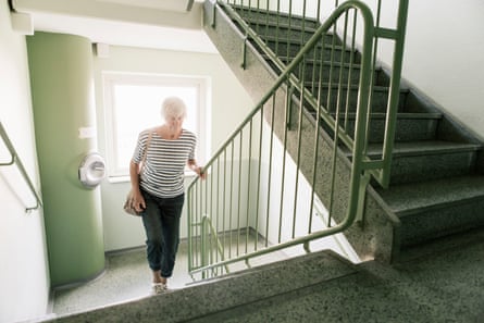 Senior woman walking on staircase in apartment building.
