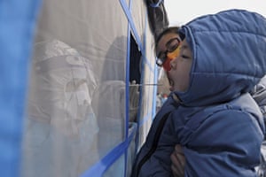 In this photo released by Xinhua News Agency, a worker wearing a protection suit collects samples from a child during a mass coronavirus testing in north China’s Tianjin municipality.
