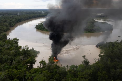 Smoke rises above a burning vessel on a bend in the river