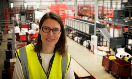 Majonne Frost smiles for a picture, wearing a yellow hi-vis vest, in a factory with machinery behind her