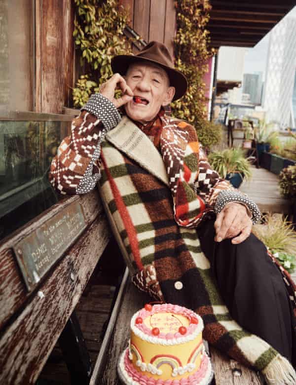 Slice of life: Sir Ian wears blanket coat by Bethany Williams (selfridges.com), scarf by paulsmith.com, trousers by Séfr (matchesfashion.com) and hat, model’s own. Cake by covenbakery.co.uk.