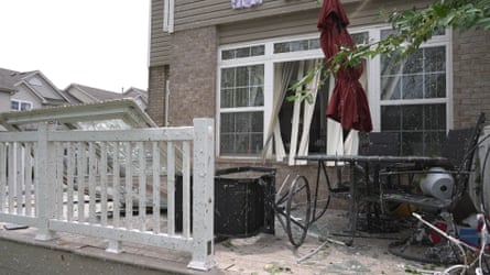 window leaning against porch outside home surrounded by rain and debris during storm