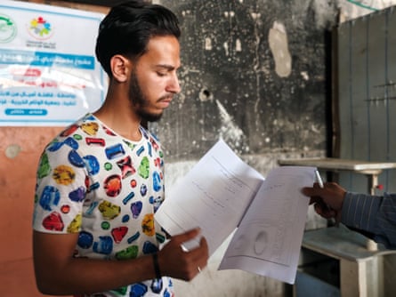 Radwan stands looking at some papers he is holding