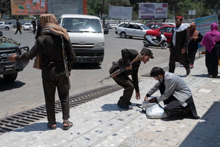 Taliban security search the belongings of a pedestrian along a blocked street in June 2022
