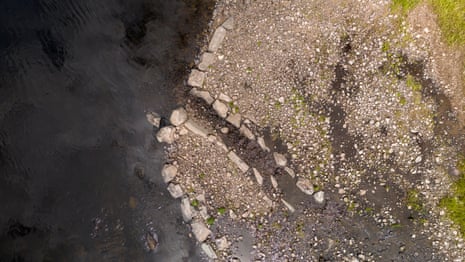 Aerial view of larger stones laid out in a path along a riverbank