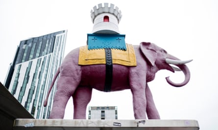 A statue of a pink elephant bearing a castle turret on its back