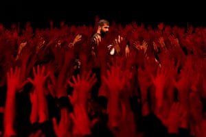 A man stands in the centre as people raise their hands during a ceremony