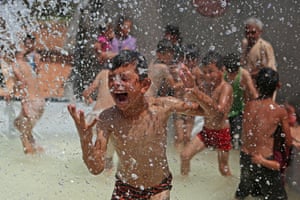 A boy is sprayed with water in a portable swimming pool set up by volunteers at a camp for the displaced in the rebel-held town of Kafr Yahmul, Idlib, Syria