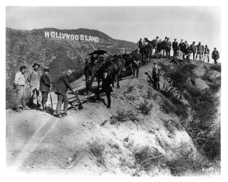 People and horses on a hilltop below the Hollywoodland sign