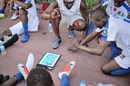 The coach of the Gambia team explains some tactics during the halftime