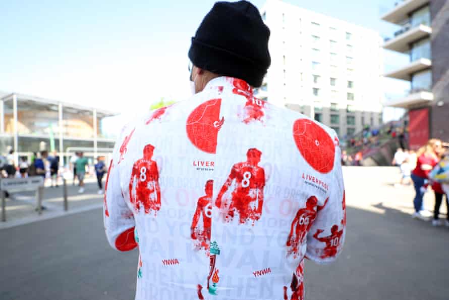 A Liverpool fan wears a suit with images of current and former players .