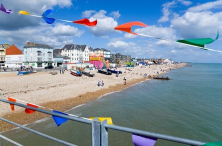 Looking from the pier towards the shingle beach at Bognor Regis, with bunting flapping in the foreground. There are boats and bathers on the beach