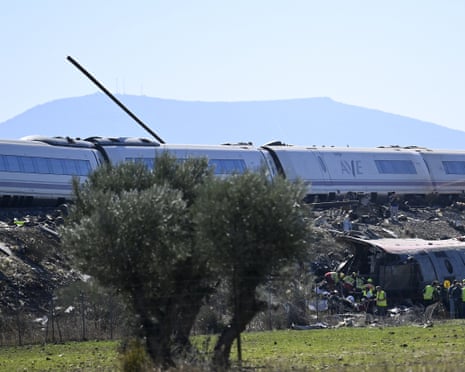 Derailed train carriages lie on an embankment as rescue workers search the wreckage in Toledo