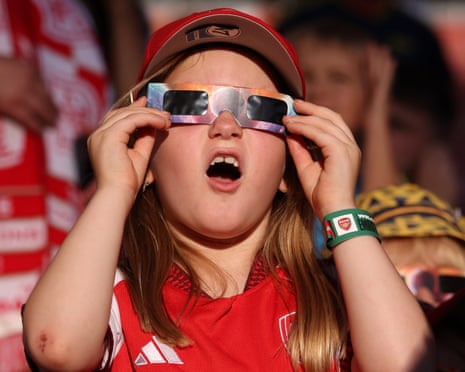 A young fan of Arsenal wears protective glasses to watch the solar eclipse ahead of the pre-season friendly match between Arsenal FC and Como 1907 at Emirates Stadium, London.