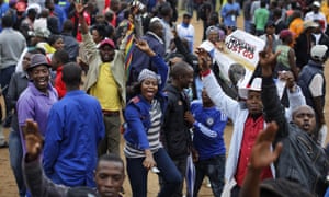 Protesters dance and sing, one holding a poster asking President Mugabe to step down, at a demonstration at Zimbabwe Grounds in Harare