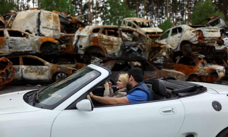 A couple sit in a car at a storage area for civilian vehicles damaged and destroyed by Russian attacks in Bucha.
