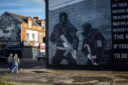 women walk past a mural in Northern Ireland
