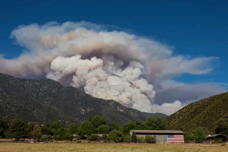 Smoke from the Apple fire rises behind a farm in Cherry Valley, California.
