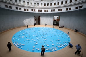 View from above of people looking at big blue circle with white dishes in it
