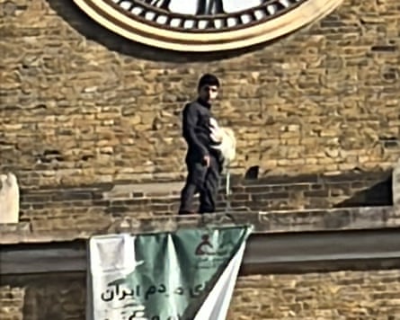 The protestor underneath the clock on the tower at King’s Cross station