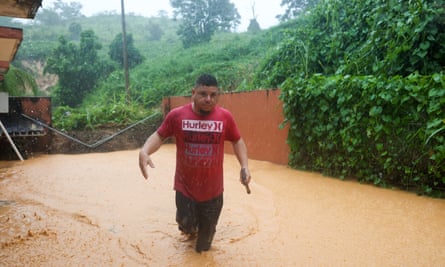A man walks on a road flooded by Hurricane Fiona in Cayey, Puerto Rico.