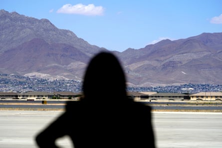 Silhouette of a woman in foreground with mountains and blue sky far beyond.