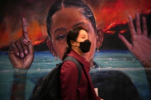 A Cop26 delegate walks past a mural at the SEC