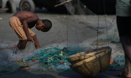 A Rohingya refugee boy scours a fishing net for leftovers