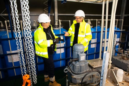 Ryan Law, chief executive of GEL, alongside Charlotte Wilkins, who is in charge of the lithium plant, stand in front of equipment and talk.