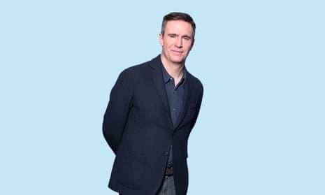 Jack Davenport wearing a navy shirt and jacket, against a pale blue background