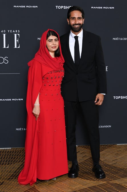 Malala Yousafzai, wearing a bright=red dress amd headscarf with Asser Malik, wearing a black suit and tie with a white shirt at the Elle Style Awards