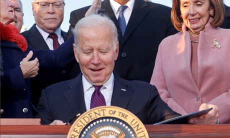 Joe Biden celebrates with lawmakers including the House speaker, Nancy Pelosi, before signing the Infrastructure Investment and Jobs Act on the South Lawn at the White House.