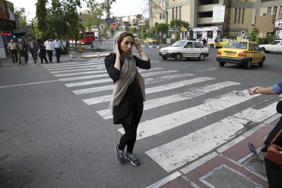 An Iranian woman adjusts her head scarf while crossing a street in downtown Tehran, Iran.