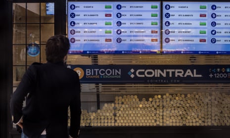 A man looks at cryptocurrency prices in a window of a cryptocurrency exchange office