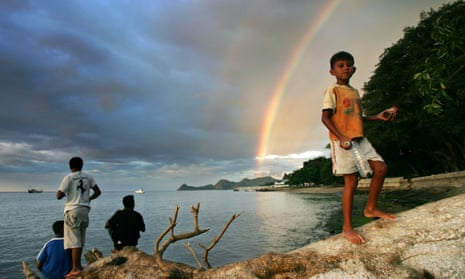 An East Timorese youth walks as a streak of rainbow is seen in the background in Dili, Timor-Leste’s capital. The 
