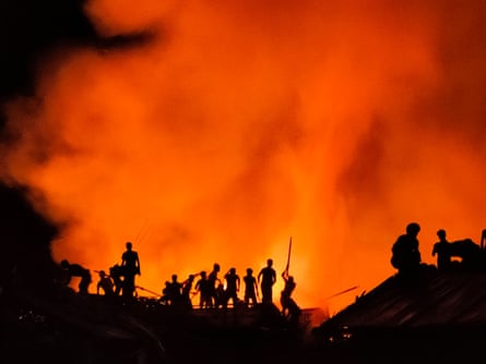Rohingya-flyktninger prøver å slukke en brann som brøt ut i Kutupalong i juli 2021 ved å bruke trebiter og bambus. Et fotografi av Sahat Zia Hero.