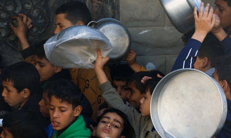 Children holding out empty vessels in hope for receiving food in Gaza