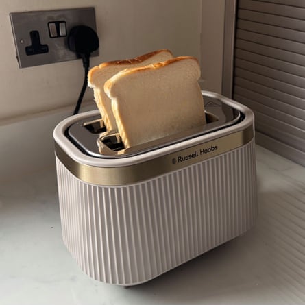 A beige Russell Hobbs Brontë 2S Toaster with two slices of bread popping out of the top on a worktop