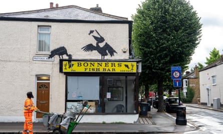 A mural of two pelicans eating fish above a yellow fish-and-chip shop sign